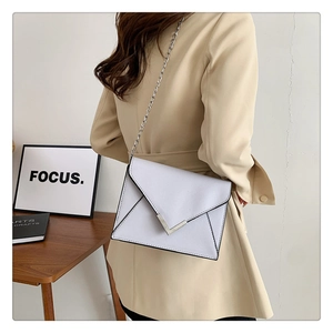 Detailed view of a white envelope chain bag with V-shaped metal buckle and silver chain