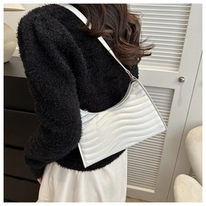 Detail of white underarm bag featuring wave quilted texture and leather shoulder strap