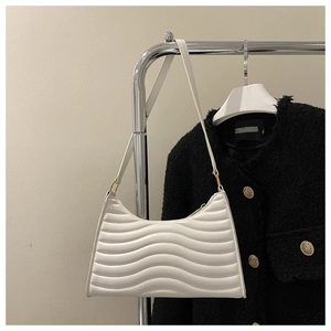 Detailed view of white half-moon shoulder bag with unique horizontal wavy quilting pattern