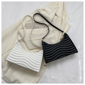 Close-up of ripple quilted baguette bags in black and white on a beige blazer