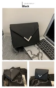 Detail view of black Saffiano leather crossbody bag with silver V-clasp and chain strap