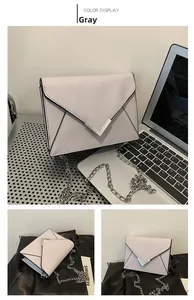 Detail view of a gray cross-grain leather envelope bag with silver V-shaped buckle hardware
