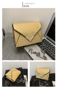 Detail of gold envelope chain bag with V-shaped metal hardware and cross-grain texture