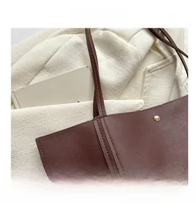 Detail of dark brown leather tote showing fine stitching and minimalist gold stud