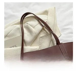 Detail showing deep brown leather tote with pebble texture and gold metal studs