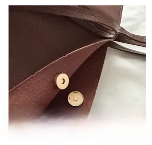 Detail of brown leather tote showing magnetic metal closure and suede lining texture
