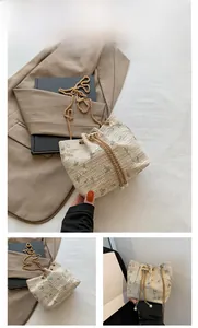 Close-up of beige woven bucket bag with floral embroidery, gold chain and pearl detail