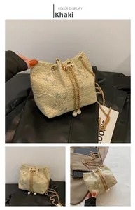 Detail of khaki straw bucket bag featuring floral embroidery and golden pearl chain