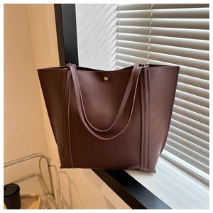 Detail view of the magnetic closure and matte PU leather texture on this dark brown tote bag