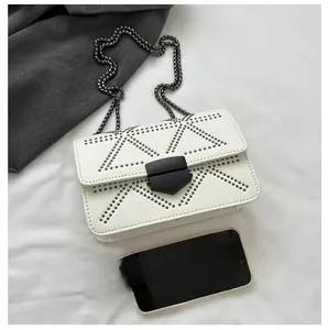 White leather crossbody bag with metal rivets and phone size comparison view