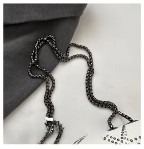 Detail of white leather crossbody bag with gunmetal square chain and metal rivets