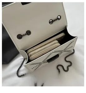 Interior view showing the capacity of a white leather crossbody bag with chain and studs