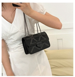 Detail of crossbody bag with silver rivet geometric patterns and metallic chain strap