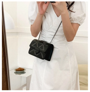 Mirror selfie showing the fit of a black crossbody bag with silver stud triangles