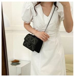 Detail of black crossbody bag with silver rivet triangle pattern and metal chain strap