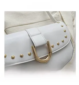 Gros plan détaillé du sac bandoulière en cuir blanc avec rivets et boucle en métal