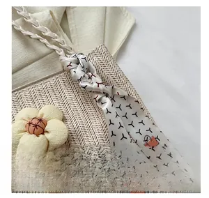 Detail of woven straw tote bag featuring fabric flower accent and printed silk scarf handle