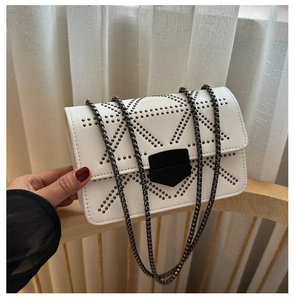 Detail of white rectangle crossbody bag with silver studs and matte black shield buckle