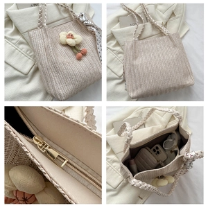 Detail of woven straw tote bag showing metal zipper closure and floral decoration