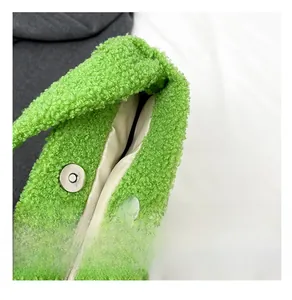 Detail shot of the magnetic snap closure and plush teddy fabric on a green shoulder bag