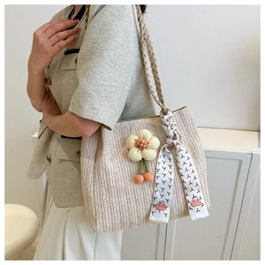 Detail of straw tote bag with 3D flower charm and geometric pattern silk scarf on handle