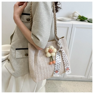 Detail of woven beige tote bag featuring a large 3D flower and colorful silk scarf