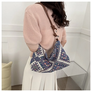 Close-up of bohemian woven hobo bag with geometric ethnic patterns and brown leather strap