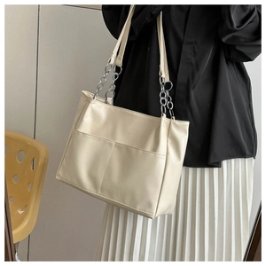 Detail of cream white tote bag featuring front slip pocket and silver metal chain strap
