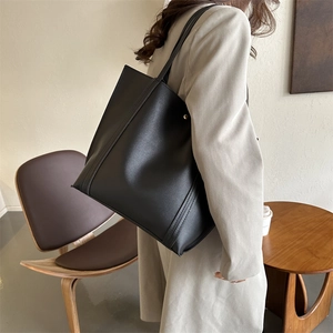 Minimalistische schwarze PU-Leder-Einkaufstasche mit vertikalen Nähten am Modell