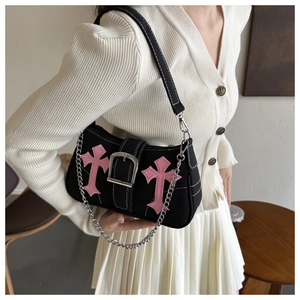 Detail of black canvas shoulder bag with pink cross patches and silver chain strap