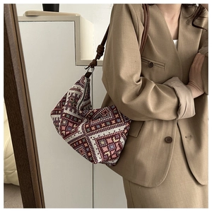 Detail of bohemian geometric jacquard underarm bag with decorative knotted leather strap