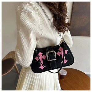 Close-up of black canvas shoulder bag with pink cross leather patches and silver chain