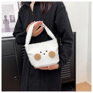 Close-up of white plush handbag with cute cartoon face held by model in knit sweater