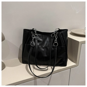 Macro detail of black leather tote bag with silver chain ring and vertical stitching