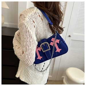 Detail view of blue canvas shoulder bag with pink cross patches and metal buckle
