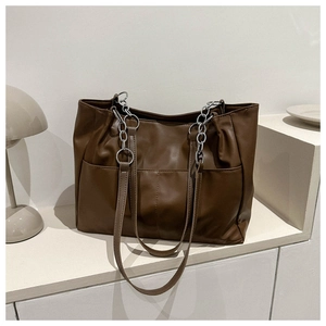 Detail view of brown large tote bag showing soft pleated faux leather and metal chain straps