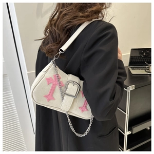 Detail of off-white canvas shoulder bag with pink cross embroidery and silver chain