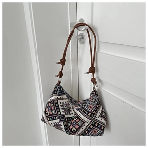 Close-up of ethnic geometric canvas bag with colorful woven pattern and leather strap