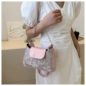 Détail du sac floral rose avec chaîne fleurie dorée et logo blanc sur le rabat