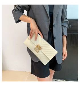 Detail der cremefarbenen Umschlagtasche mit V-Steppung und goldener Metallschnalle