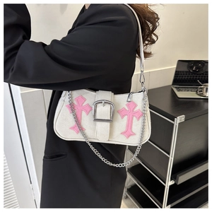 Close-up of white underarm bag with pink cross appliques and oversized silver buckle