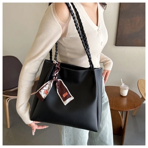 Black tote bag with woven straps and printed silk scarf shown in a lifestyle cafe setting