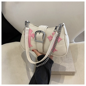 Close-up of minimalist cream canvas underarm bag with pink leather cross appliques and chain