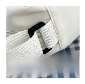 Close-up of durable shoulder strap connection and black plastic buckle on white nylon bag