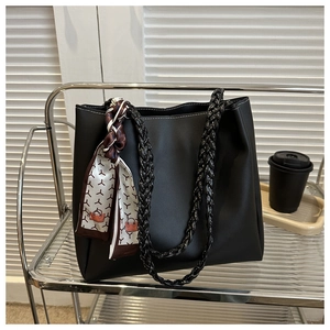 Detail of black tote bag featuring white contrast stitching and a silk patterned scarf