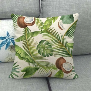 Detail of linen cushion cover showing tropical green leaves and coconut prints on sofa