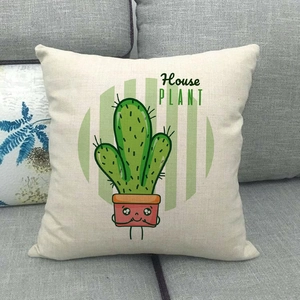 Detail of linen pillowcase with green cartoon cactus print on a grey fabric sofa