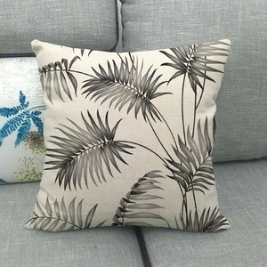 Detailansicht eines Leinen-Kissenbezugs mit Palmenblattmuster auf einem grauen Sofa
