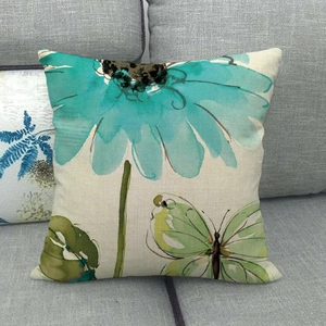 Federa per cuscino in lino con fiore blu ad acquerello su un divano grigio moderno