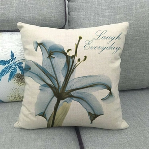 Detail of linen cushion cover featuring lily floral print and Laugh Everyday text on sofa